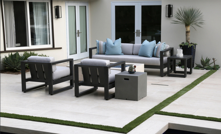 Modern outdoor patio furniture set with gray frames and light blue cushions on a tiled patio in Clearwater Beach, Florida.